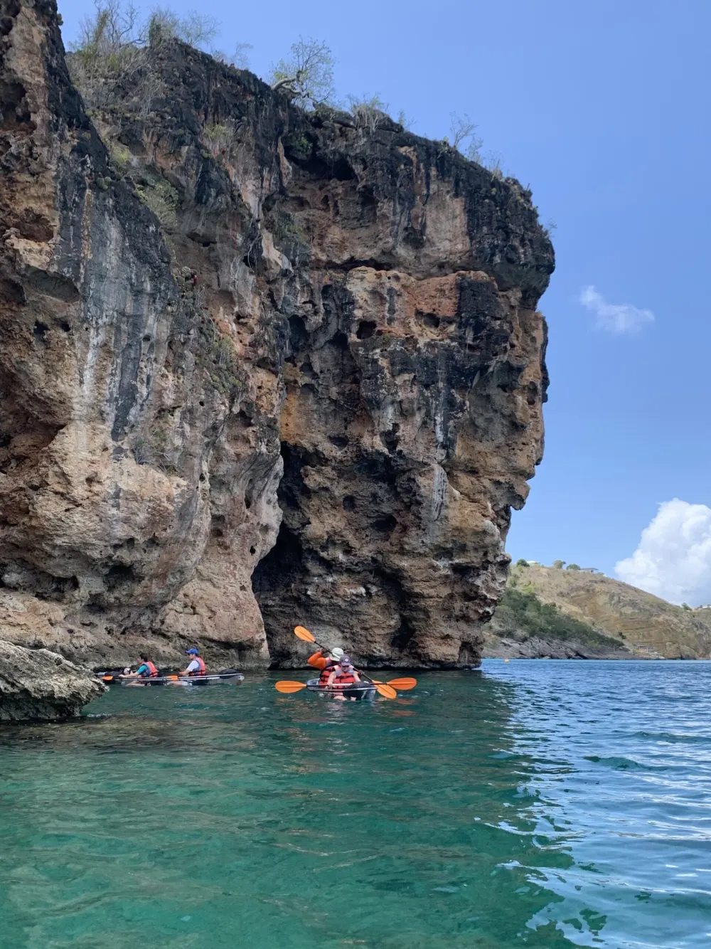 Kayakers paddling beneath the tall limestone cliffs of Crocus Bay