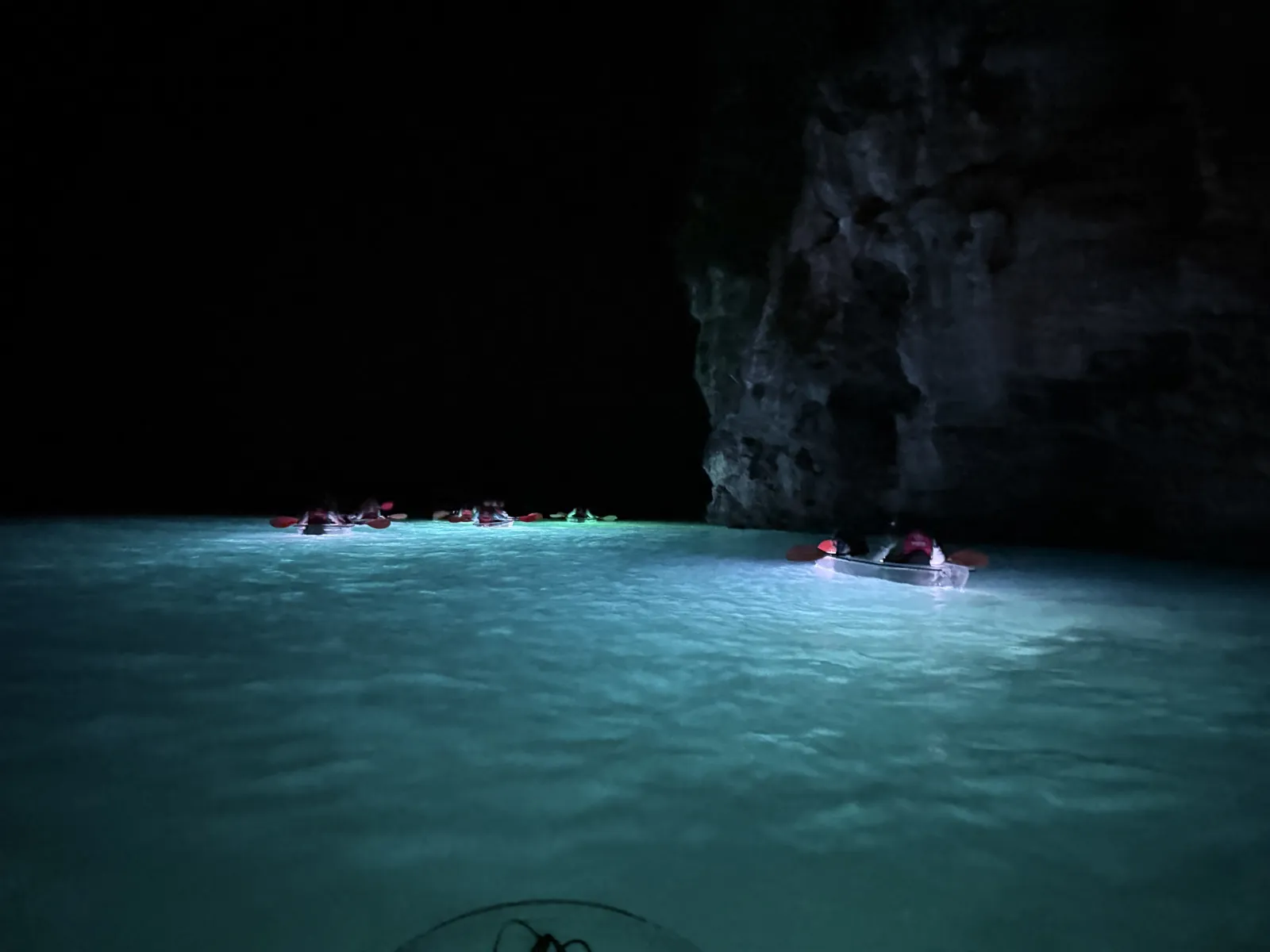 Illuminated clear kayaks lighting the water turquoise at the foot of the cliffs